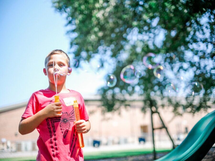 Young boy playing with bubbles outdoors at STEAMCamp