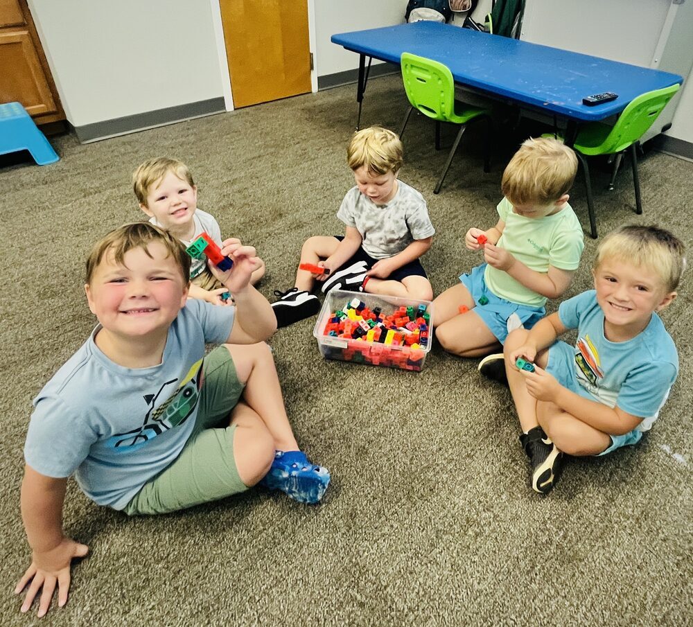 Group of young boys sitting together building with colorful blocks at STEAMCamp