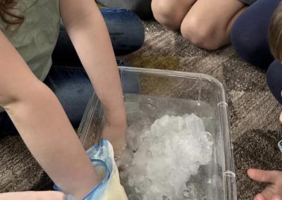 Kids discovering the science of insulation during a blubber experiment at STEAMCamp