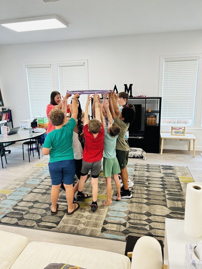 Group of campers and instructor holding a hula hoop up together in a teamwork challenge at STEAMCamp