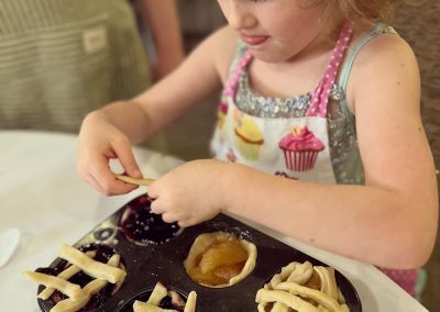 Young girl in cupcake apron making mini pies at STEAMCamp