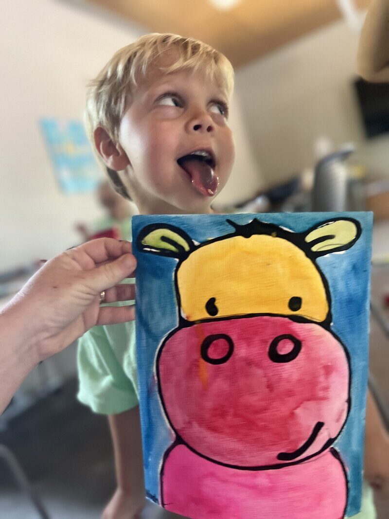 Toddler painting a colorful hippo at STEAMCamp